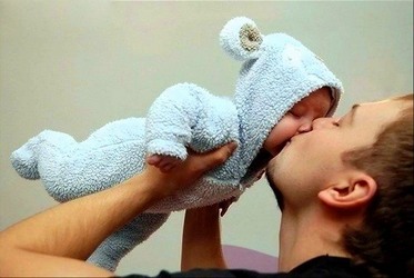 папа целует малыша в пижамке